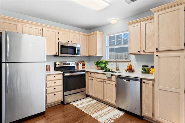 kitchen with dark wood-style floors, appliances with stainless steel finishes, light countertops, and a sink