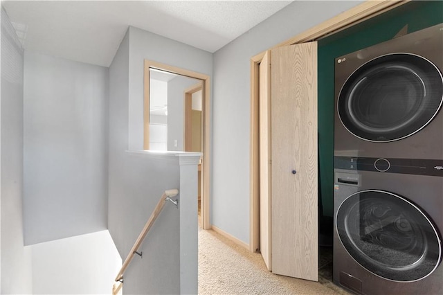 laundry room with laundry area, carpet floors, stacked washer and clothes dryer, and baseboards