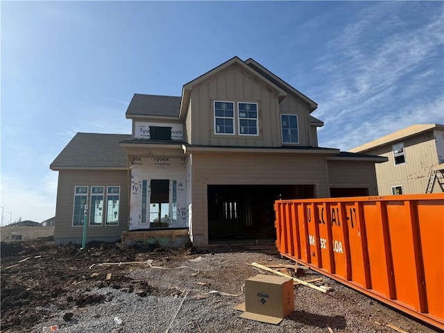 view of front facade with a garage, board and batten siding, and fence