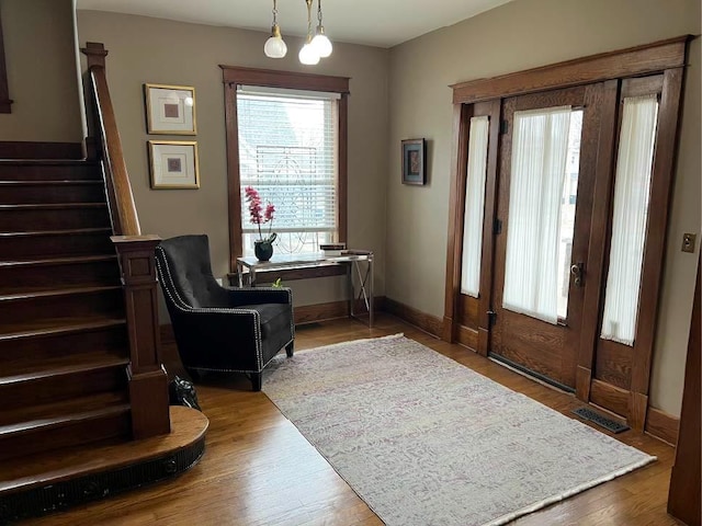 entryway featuring visible vents, light wood-style flooring, baseboards, and stairs