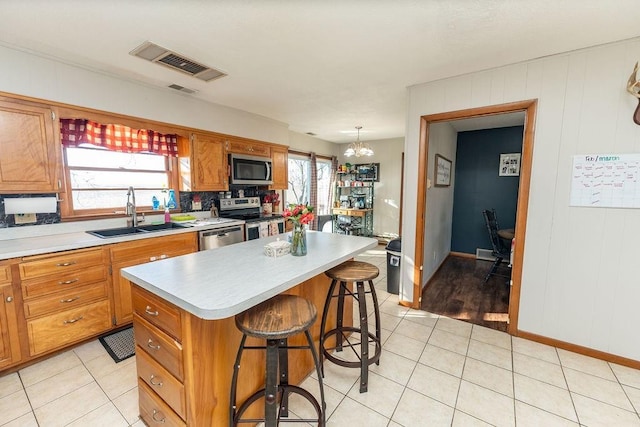 kitchen with visible vents, appliances with stainless steel finishes, a center island, light countertops, and a sink