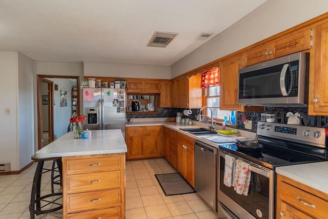 kitchen featuring stainless steel appliances, light countertops, a sink, and visible vents