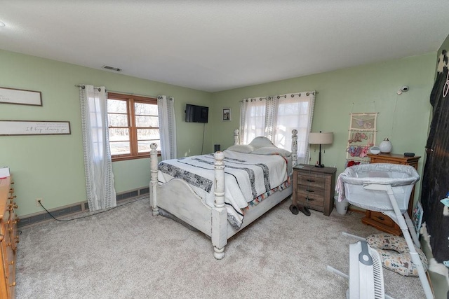 bedroom with light colored carpet, visible vents, baseboards, and multiple windows