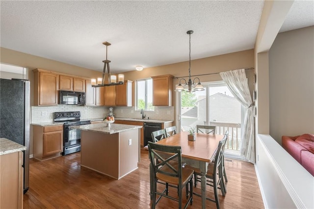 1716 NW 54th Ter, Kansas City, MO 64118 - kitchen featuring black appliances, backsplash, a center island, a chandelier, and a textured ceiling