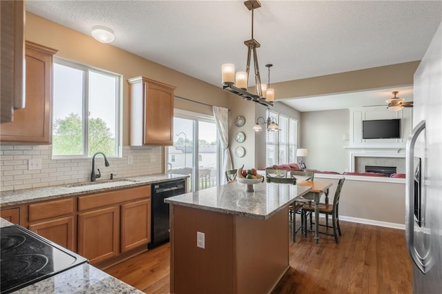 1716 NW 54th Ter, Kansas City, MO 64118 - kitchen featuring dishwasher, a sink, open floor plan, a fireplace, and wood finished floors