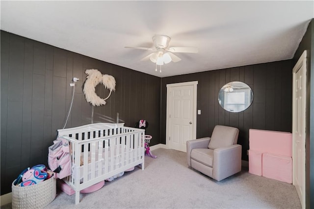 carpeted bedroom with a ceiling fan and a nursery area