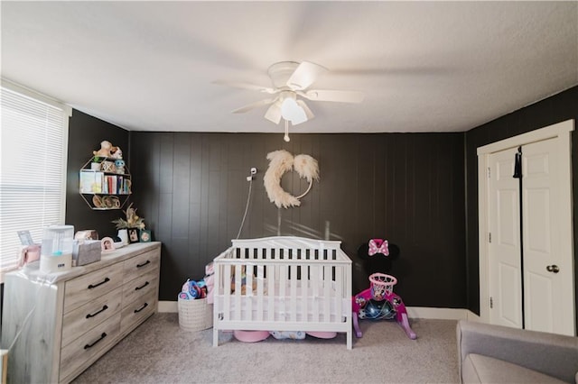 bedroom with carpet floors, a crib, and a ceiling fan