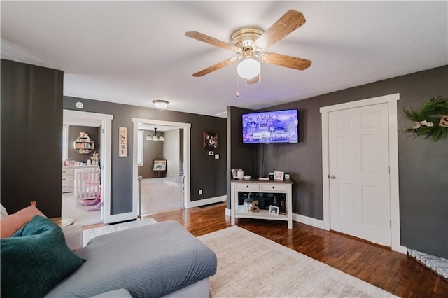 living area featuring a ceiling fan, baseboards, and wood finished floors