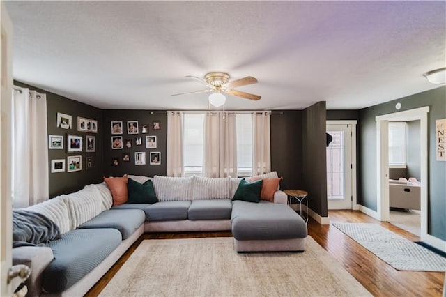 living room featuring plenty of natural light, wood finished floors, a ceiling fan, and baseboards