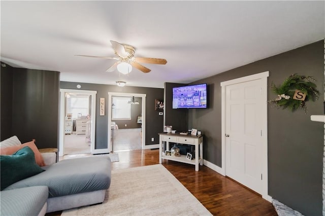 living room with wood finished floors, a ceiling fan, and baseboards