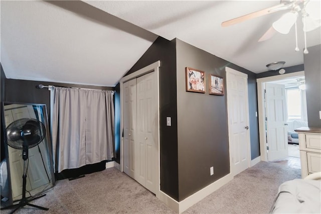 bedroom featuring lofted ceiling, a closet, a ceiling fan, light carpet, and baseboards