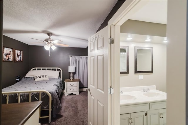 bedroom with dark carpet, a textured ceiling, a sink, and ceiling fan