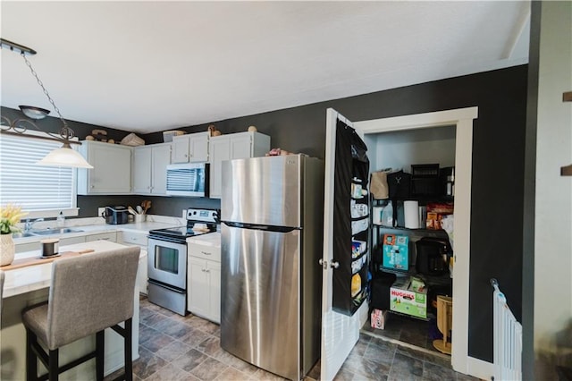 kitchen featuring stainless steel appliances, stone finish floor, a sink, and light countertops