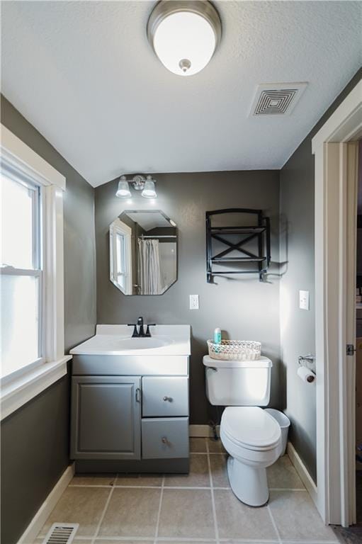 bathroom featuring visible vents, toilet, vanity, baseboards, and tile patterned floors