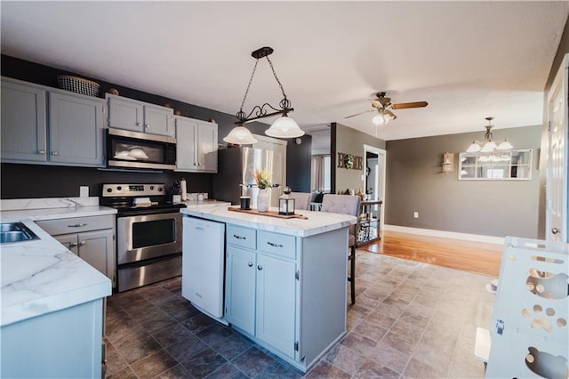 kitchen featuring baseboards, appliances with stainless steel finishes, a center island, hanging light fixtures, and light countertops