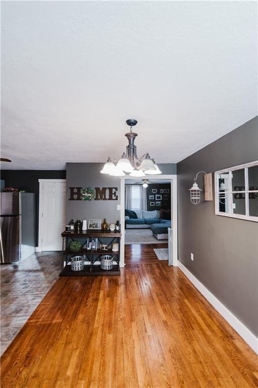 unfurnished dining area featuring wood finished floors, baseboards, and an inviting chandelier