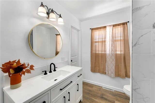 bathroom featuring toilet, visible vents, wood finished floors, and vanity