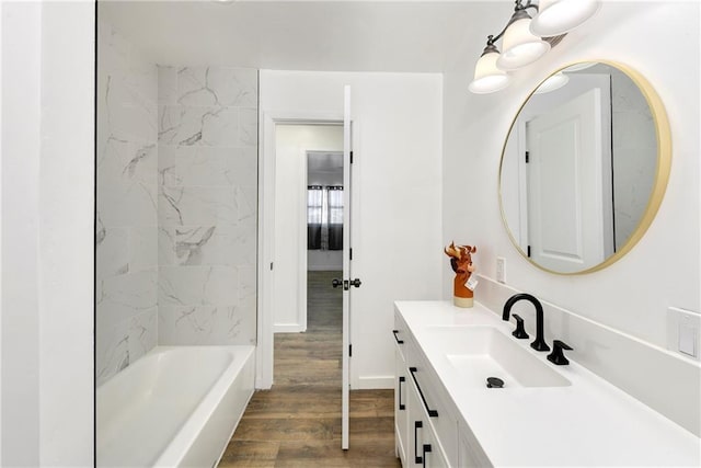 bathroom with baseboards, shower / bathing tub combination, wood finished floors, and vanity