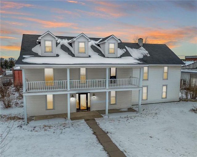 snow covered house featuring a balcony