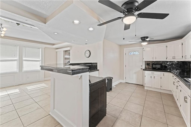 kitchen with light tile patterned floors, backsplash, and white cabinets