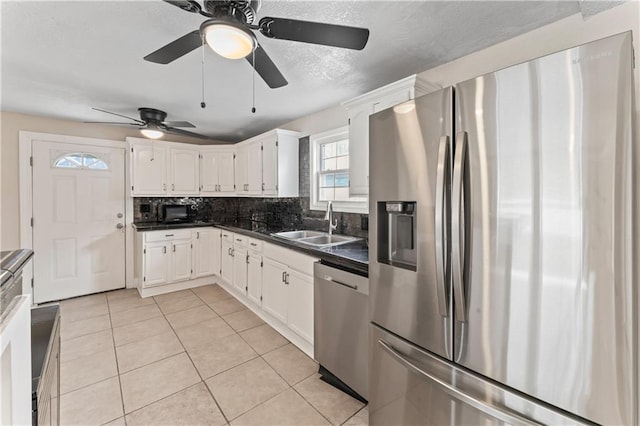 kitchen with a sink, white cabinets, appliances with stainless steel finishes, decorative backsplash, and dark countertops