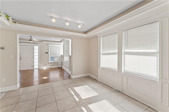 spare room featuring light tile patterned floors, ceiling fan, a tray ceiling, and baseboards