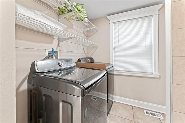 laundry room with tile patterned flooring, laundry area, visible vents, baseboards, and washer and clothes dryer