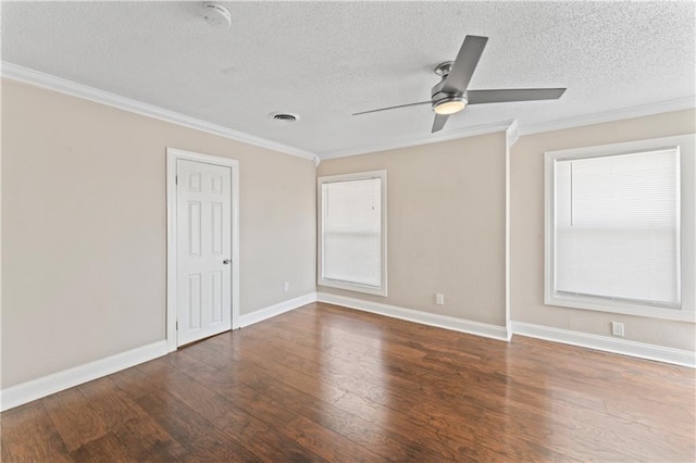 empty room featuring a textured ceiling, wood finished floors, visible vents, baseboards, and crown molding