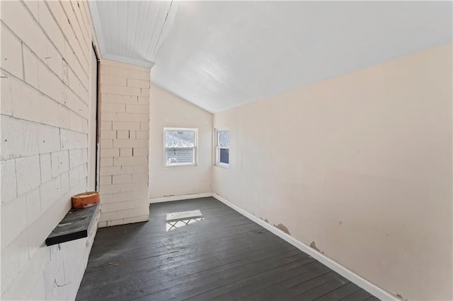 unfurnished living room featuring lofted ceiling, baseboards, and dark wood-style flooring