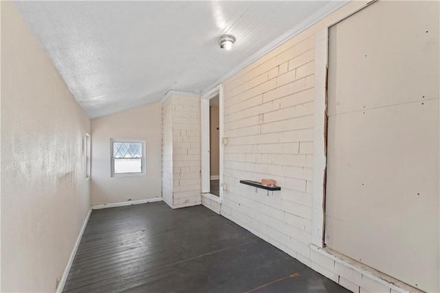 spare room featuring vaulted ceiling, wood finished floors, and baseboards