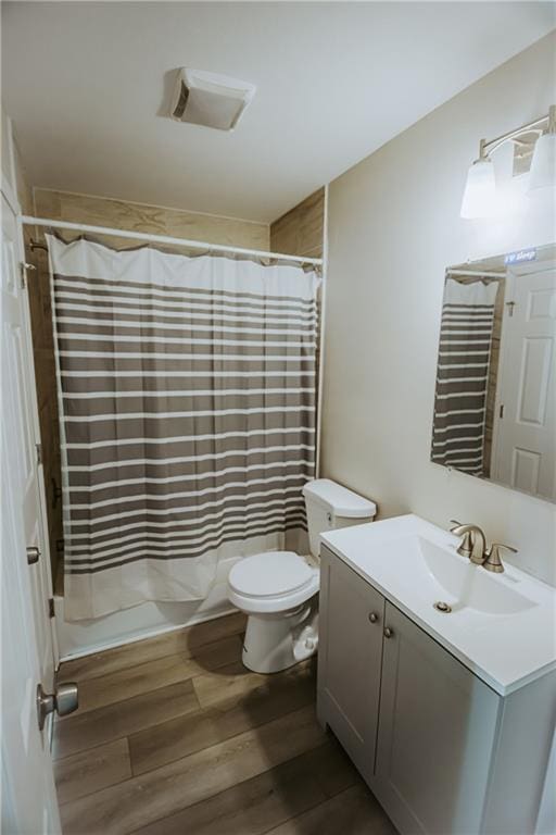 bathroom featuring toilet, curtained shower, wood finished floors, and vanity