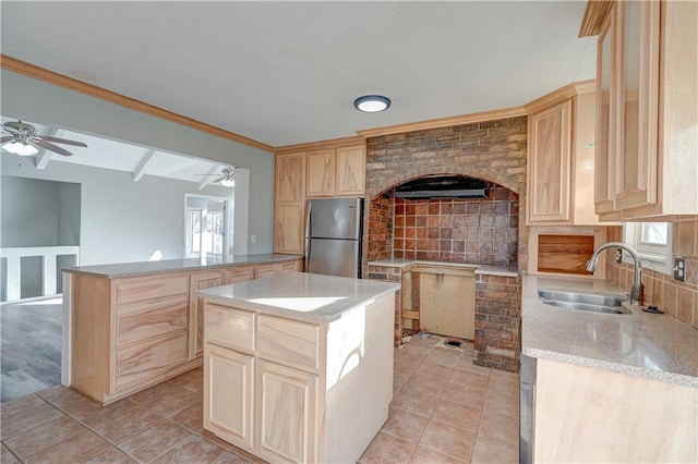 kitchen with light tile patterned floors, a ceiling fan, light brown cabinets, freestanding refrigerator, and a sink