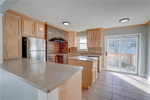 kitchen with a sink, tasteful backsplash, a center island, freestanding refrigerator, and light tile patterned floors