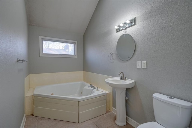 bathroom with a textured wall, toilet, a jetted tub, and tile patterned flooring