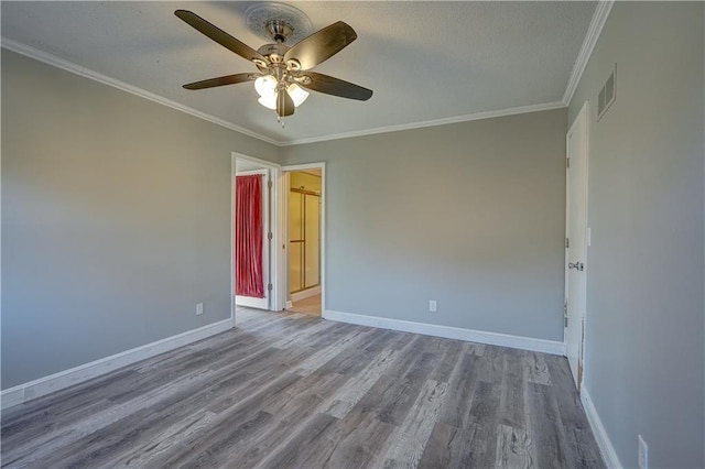 spare room featuring wood finished floors, visible vents, baseboards, and ceiling fan