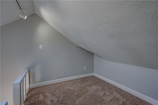 additional living space featuring lofted ceiling, baseboards, carpet floors, and a textured ceiling