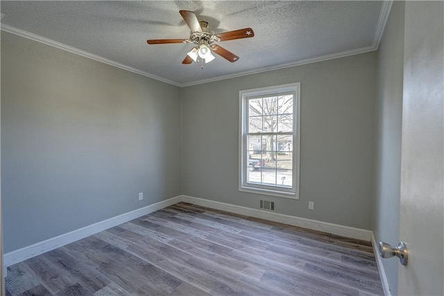 unfurnished room with visible vents, crown molding, baseboards, wood finished floors, and a textured ceiling