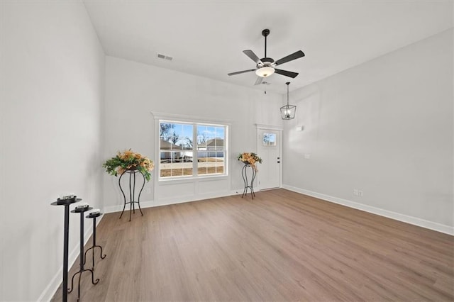 spare room featuring a ceiling fan, visible vents, baseboards, and wood finished floors