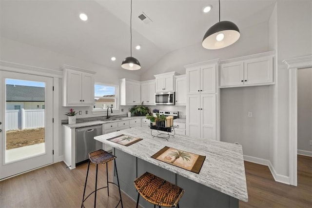 kitchen with visible vents, vaulted ceiling, stainless steel appliances, white cabinetry, and a sink