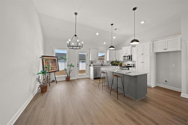 kitchen featuring appliances with stainless steel finishes, white cabinetry, a kitchen island, and wood finished floors