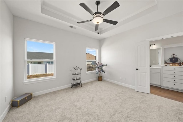 unfurnished bedroom with a tray ceiling, visible vents, a ceiling fan, carpet flooring, and baseboards