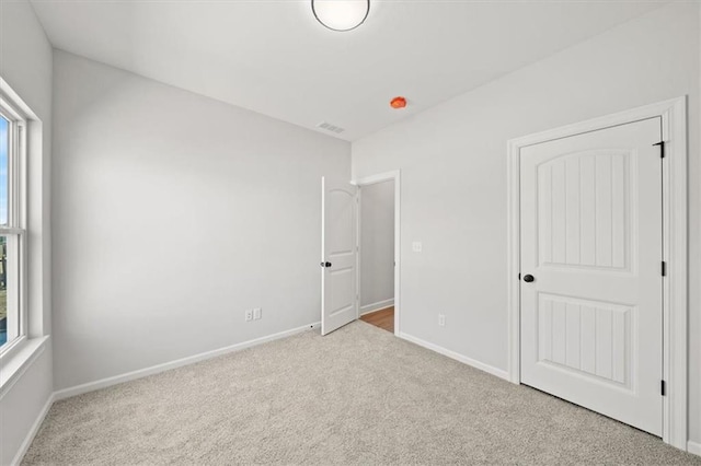 unfurnished bedroom featuring carpet flooring, visible vents, and baseboards