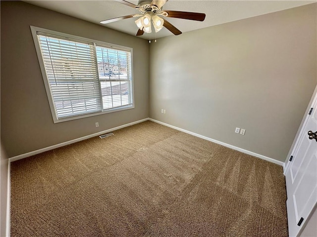 carpeted spare room with ceiling fan, visible vents, and baseboards