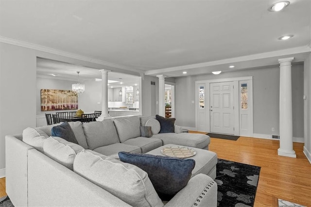 living room with ornate columns, baseboards, and light wood-style floors