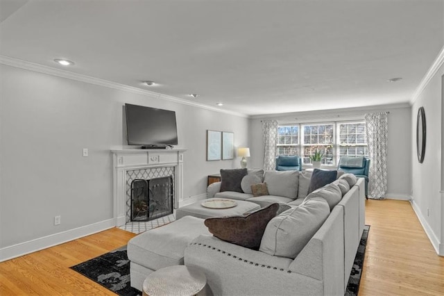 living area featuring crown molding, recessed lighting, a tiled fireplace, light wood-type flooring, and baseboards