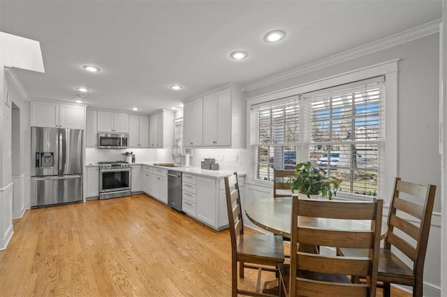 kitchen featuring a wealth of natural light, appliances with stainless steel finishes, a sink, and ornamental molding