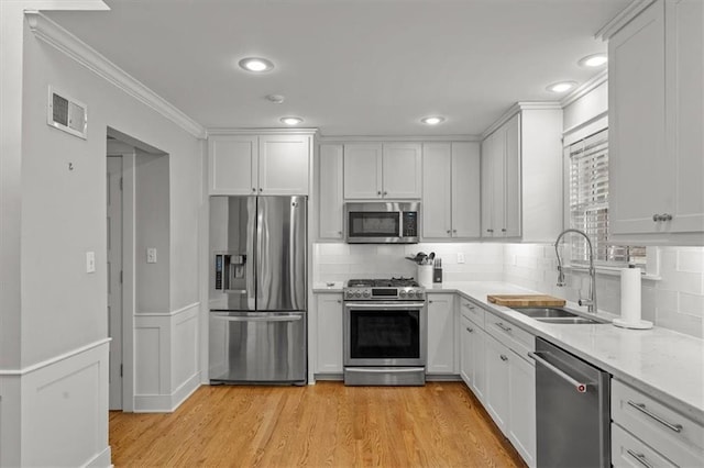 kitchen with visible vents, appliances with stainless steel finishes, white cabinets, a sink, and light wood-type flooring