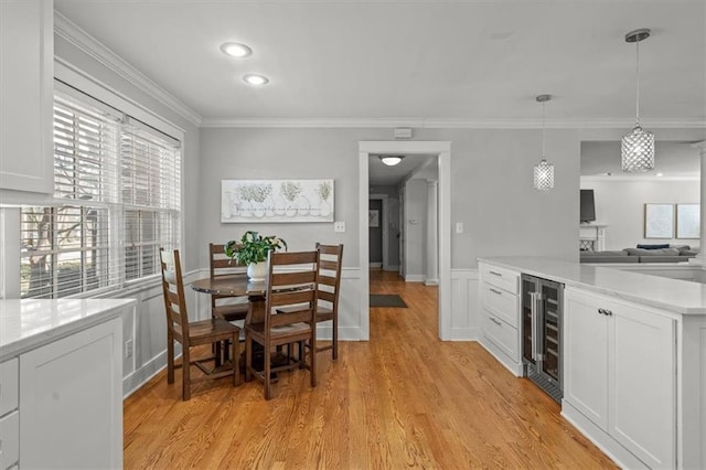 dining room with light wood-style floors, recessed lighting, beverage cooler, and crown molding