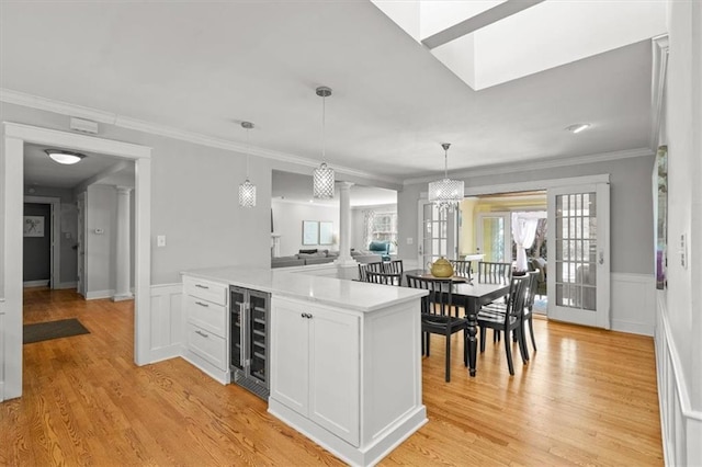 kitchen with beverage cooler, white cabinetry, light wood-style flooring, and light countertops