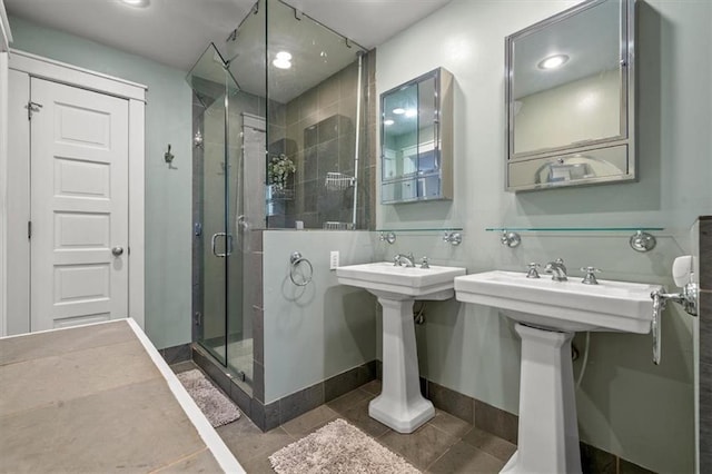 full bath with baseboards, a sink, a shower stall, and tile patterned floors